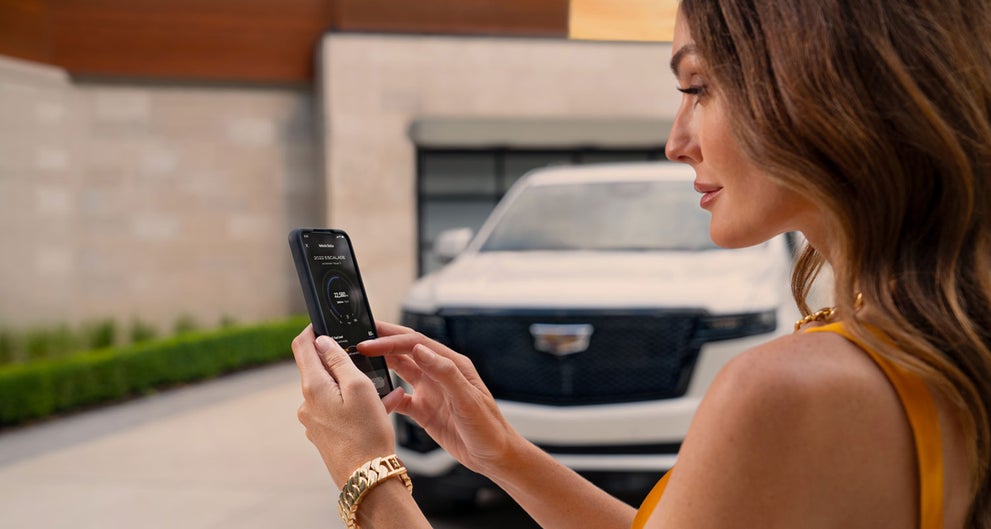 lady checking her mobile with a Cadillac vehicle background | Cummins Cadillac in Weatherford OK